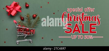 Einkaufswagen mit Weihnachtsdekor und Geschenk auf grünem Hintergrund. Weihnachtsangebot Stockfoto