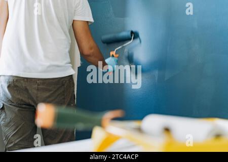 kaukasischer bärtiger Mann, der die Wand mit Malerwalze malte. Malerwohnung, renovierendes Haus Stockfoto