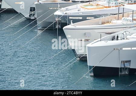 Sonnenstrahlen auf Hochglanzbooten, azurblaues Wasser, Ruhe im Hafen Herkules, Bögen von verankerten Booten an sonnigen Tagen, Megayachten, Monaco, Monte-Carlo Stockfoto