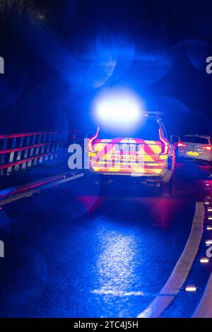 Polizeiauto mit blauen blinkenden Lichtern, die auf einen Notfall in der Nacht reagieren - Glasgow, Schottland, Großbritannien Stockfoto