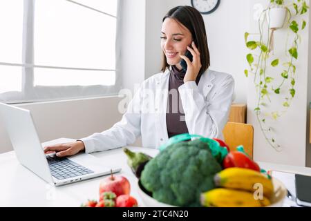 Junge lächelnde Ernährungsberaterin im Sprechzimmer Stockfoto