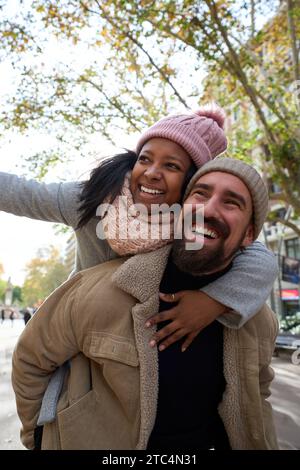 Porträt eines jungen, fröhlichen, multirassischen glücklichen Paares, das verliebt ist und sich umarmt und lächelt im Huckepack Stockfoto