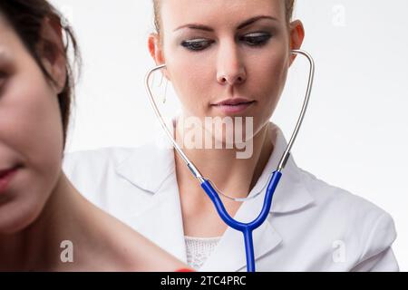 Medizinisches Fachpersonal verwendet ein Stethoskop aufmerksam auf einen Patienten und konzentriert sich dabei genau Stockfoto