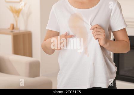 Frau zeigt Flecken von Kaffee auf ihrem Hemd drinnen, Nahaufnahme. Leerzeichen für Text Stockfoto