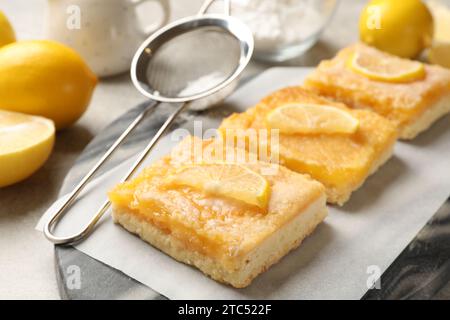 Leckere Zitronenriegel und Sieb auf dem Tisch, Nahaufnahme Stockfoto