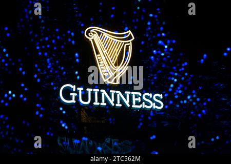 STILLWATER, MN, USA - 7. DEZEMBER 2023: Guinness Stout Getränkeschild mit reflektierten Weihnachtslichtern im Fenster. Stockfoto