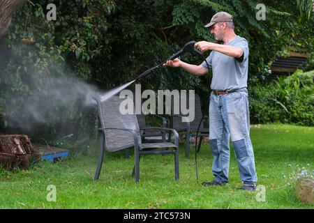 Reinigung von Gartenmöbeln mit einem Wasserstrahler bereit für den Sommer Stockfoto