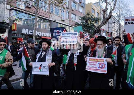 Istanbul, Türkei. Dezember 2023. Drei jüdische Personen nehmen an einem von türkischen Nichtregierungsorganisationen organisierten marsch Teil, um ihre Opposition gegen den Krieg gegen Gaza zum Ausdruck zu bringen. Im Hintergrund befindet sich ein McDonald's Restaurant, das von einer türkischen Kompanie bewacht wird. Quelle: SOPA Images Limited/Alamy Live News Stockfoto