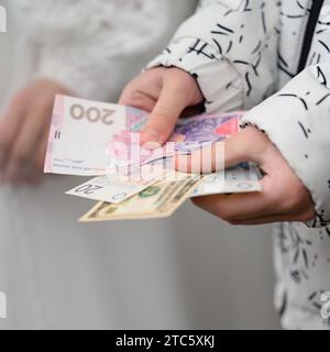 Das Kind hält ukrainische Hrywnja, polnische Zlotys und amerikanische Dollar in den Händen Stockfoto