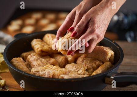 Frauenhände bereiten Kohlbrötchen mit Schweinefleisch und Reis (Sarmale) zu, ein traditionelles rumänisches Gericht Stockfoto