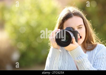 Vorderansicht eines Fotografen in einem Park, der Fotos mit spiegelloser professioneller Kamera macht Stockfoto