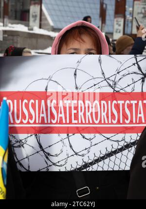 Man sieht eine Frau, die ein Plakat hält, auf dem steht, dass Russland ein Terrorstaat ist. Stockfoto