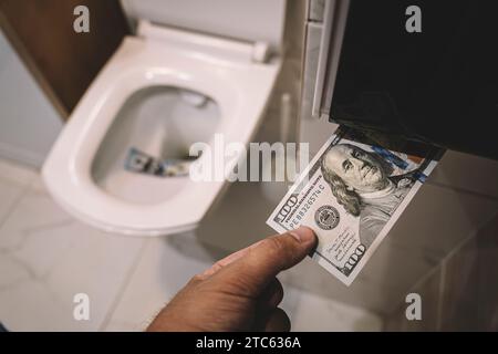 Geld in die Toilette spülen, Dollarscheine in die Toilette werfen, Verlustkonzept, Nahaufnahme, selektiver Fokus. Das Konzept sinnloser Geldverschwendung, Verlust, Usenale Stockfoto