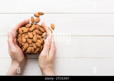 Frauenhände halten eine Holzschüssel mit Mandelnüssen. Gesundes Essen und Snack. Vegetarischer Snack mit verschiedenen Nüssen. Stockfoto