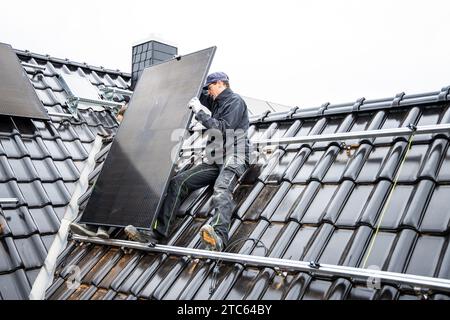 Solarmodul-Techniker, der Photovoltaikanlage auf dem Dach eines Wohnhauses installiert Stockfoto