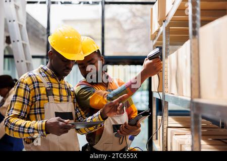 afroamerikanische Lagerverwalter scannen Pakete vor dem Versand. Mitarbeiter im Postamt, die Warenbestände mithilfe von Scannern und Barcode-Prüfung in einem digitalen Tablet durchführen Stockfoto