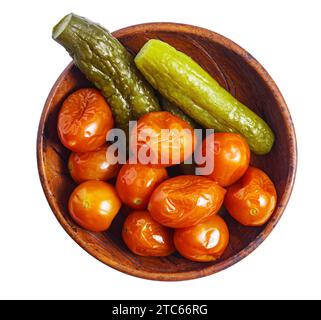 Eingelegte kleine Tomaten und Gurken in rustikaler Keramikschale, Blick von oben, isoliert Stockfoto