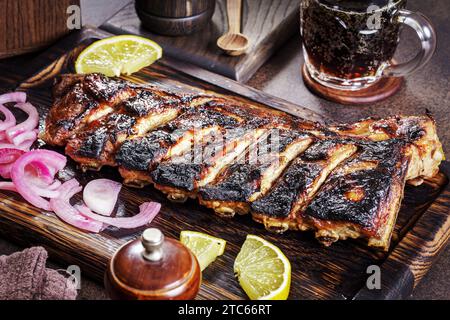 Gegrillte karamelisierte Schweinerippchen mit Zwiebeln und Zitrone auf Holztablett Stockfoto