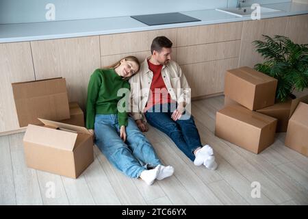 Müde Ehepaar, Frau, die vom Leben in einer neuen Wohnung träumt und auf dem Boden sitzt. Stockfoto