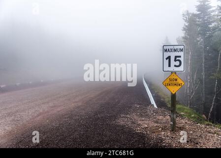 Schild für langsames Lentement Warnung gelbe Straßenschilder in selektiver Fokusansicht mit Straße im Hintergrund an nebeligen Tagen Cape Breton Island Nova Scotia Highlands C Stockfoto