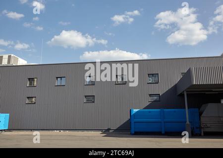 Laderampen eines Lagers. Wellblechlager Industriegebäude vor blauem, klarem Himmel Stockfoto