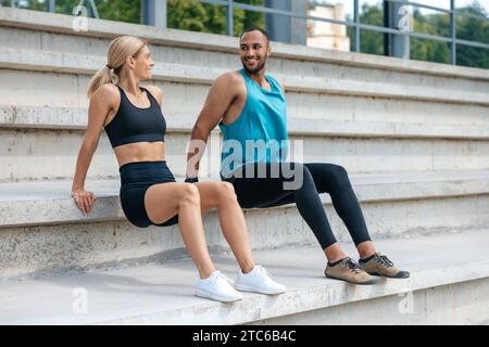 Sportliche Frau und Mann, die im Freien umgekehrte Liegestütze machen. Stockfoto