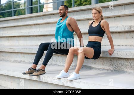 Sportliche Frau und Mann, die im Freien umgekehrte Liegestütze machen. Stockfoto