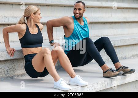 Sportliche Frau und Mann, die im Freien umgekehrte Liegestütze machen. Stockfoto