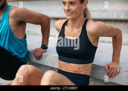 Sportliche Frau und Mann, die im Freien umgekehrte Liegestütze machen. Stockfoto