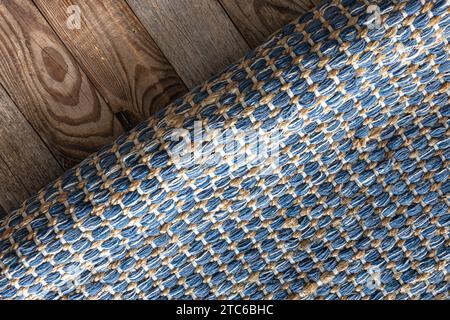 Handgewebter Teppich mit geometrischem Denim-Bereich auf Holzboden. Stockfoto