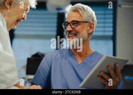 Porträt eines gutaussehenden Reifen Arztes, der mit älteren Patienten im Krankenhaus spricht. Ärztliche Beratung Ergebnis, lächelnd, lachend. Emotionale Unterstützung für Stockfoto