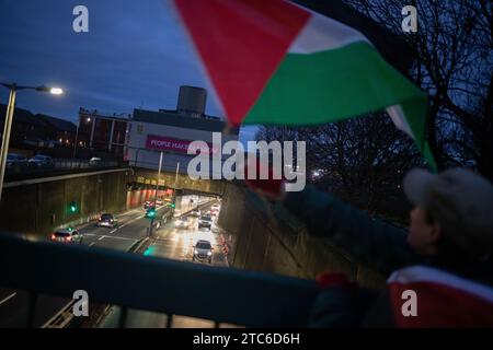 Glasgow, Großbritannien, 11. Dezember 2023. Pro-palästinensische Kundgebung fliegt Fahnen für Pendler, die über Straßen des Clyde-Tunnels zu einer Zeit des Völkermordes in Gaza, in Glasgow, Schottland, am 11. Dezember 2023 sehen. Foto: Jeremy Sutton-Hibbert/ Alamy Live News. Stockfoto