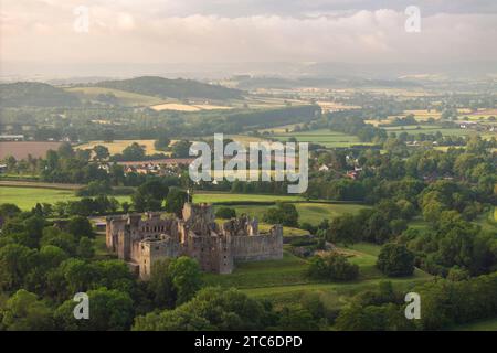 Aus der Vogelperspektive auf die Ruinen von Raglan Castle an einem nebeligen Morgen, Monmouthshire, Wales, Großbritannien. Sommer (Juni) 2023. Stockfoto