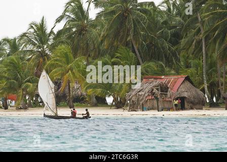 Ein traditionelles Fischerboot fährt an einem kleinen Dorf auf den San Blas Inseln, Panama, vorbei. Stockfoto