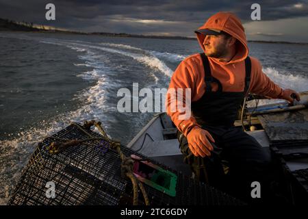 Kommerzieller Fischer, der ein Fischerboot mit stürmischem Himmel fährt Stockfoto