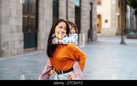 Glückliche südostasiatische Mutter mit ihrer Tochter, die Spaß im Stadtzentrum hat - nette Familie draußen Stockfoto