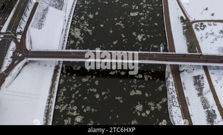 Drohnenfotografie von einer Fußgängerbrücke über einem Fluss in einer Stadt während des Winters Stockfoto