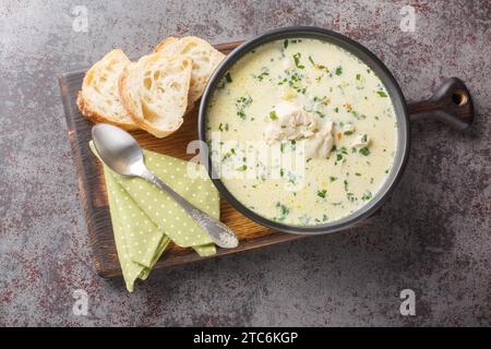 Rumänische Hühnersuppe Ciorba Radauteana mit Gemüse und Sauerrahm auf dem Teller auf dem Tisch. Horizontale Draufsicht von oben Stockfoto