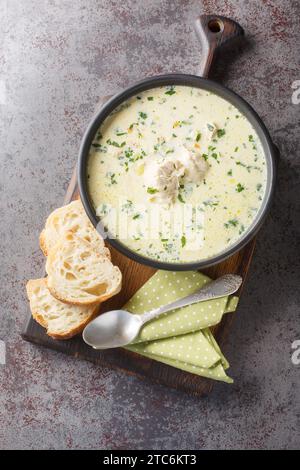 Rumänische Hühnersuppe namens Ciorba Radauteana aus der Nähe auf dem Teller auf dem Tisch. Vertikale Draufsicht von oben Stockfoto