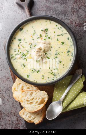 Rumänische Sauerrahm Knoblauch Hühnersuppe Radauteana Nahaufnahme auf dem Teller auf dem Tisch. Vertikale Draufsicht von oben Stockfoto