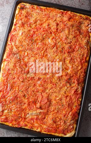 Sfincione oder sizilianische Pizza mit hausgemachter Hefekruste und Tomatenzwiebelsauce, Käse und Sardellen auf einem Backblech auf dem ta Stockfoto