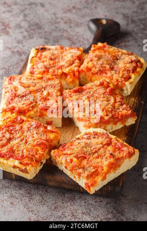 Sfincione Siciliano ist eine Pizza im sizilianischen Stil mit knusprigen Brotkrumen, geriebenem Käse und Oregano auf dem Holzbrett auf dem Tisch. Ver Stockfoto