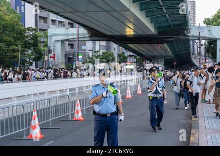 Osaka, Japan - 25. Juli 2023 : Polizist lenkt die Menschenmenge, die während des Tenjin Matsuri Festivals auf der Straße läuft. Stockfoto