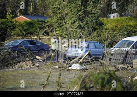 Ein Mann fotografiert ein beschädigtes Auto in Leitrim Village in Co Leitrim, nachdem ein Tornado und starke Winde am Sonntag Bäume abplatzten, ein Dach von einem Gebäude riss und Trümmer auf einer Straße verstreut gelassen hatten. Bilddatum: Montag, 11. Dezember 2023. Stockfoto