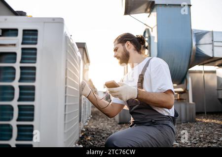 Man Builder, der Messgeräte an einem Conditioner im Freien anwendet Stockfoto