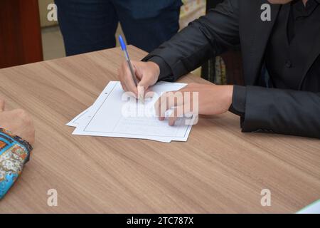 Junger Mann, der Papierdokument mit einem einfachen Stift unterschreibt. Stockfoto
