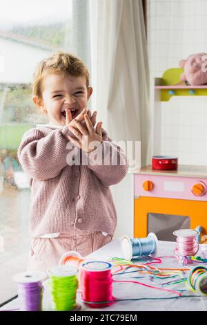 Kleines Mädchen im Spielzimmer lacht mit Händen im Mund sehr lustig Stockfoto