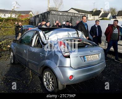 Taoiseach Leo Varadkar (dritter rechts) sieht ein Auto, das von einem Baum in Leitrim Village in Co Leitrim beschädigt wurde, nachdem ein Tornado und starke Winde am Sonntag Bäume platzten, ein Dach von einem Gebäude riss und Trümmer auf einer Straße verstreut gelassen hatten. Bilddatum: Montag, 11. Dezember 2023. Stockfoto