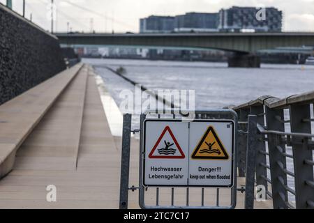 Köln, Deutschland. Dezember 2023. Schilder mit der Aufschrift "Hochwasser - Lebensgefahr" hängen an der teilweise überfluteten Treppe am Rheinufer. Eine Kombination von Regen und Tauwetter kann für Flüsse in Teilen Süd- und Westdeutschlands zu einem Problem werden. So steigen beispielsweise die Wasserstände am Rhein aufgrund der aktuellen Niederschläge im südlichen Einzugsgebiet. Quelle: Oliver Berg/dpa/Alamy Live News Stockfoto
