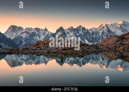 Majestätische Landschaft des Lac Blanc mit Mont Blanc Bergkette und männlichen Touristen stehen reflektiert auf dem See in den französischen Alpen bei Sonnenaufgang. Haute Savo Stockfoto